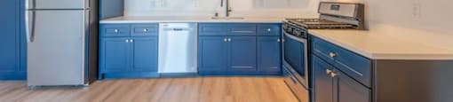 A kitchen with dark blue cabinets and stainless steel appliances.