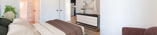 A bedroom with a bed, a chair, and a cabinet.