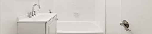 A white bathroom with a tub, sink, and toilet.