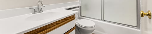 A white bathroom with a toilet, sink, and shower.