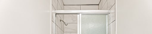 A white toilet sits next to a walk-in shower.