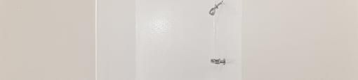 A white toilet sits next to a white shower stall.