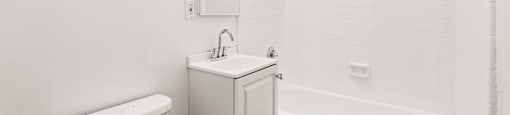 A white bathroom with a tub, toilet, and sink.