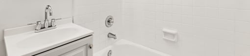 A white bathroom with a tub, sink, and mirror.