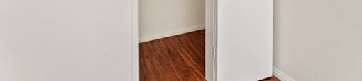A white door is open to a room with a wooden floor.