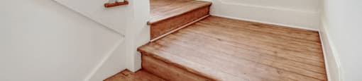 a landing with wooden stairs and a window on the top of the stairs