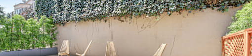 a patio with chairs and a wall with a ivy plant