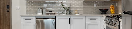 A kitchen with white cabinets and a brick backsplash.
