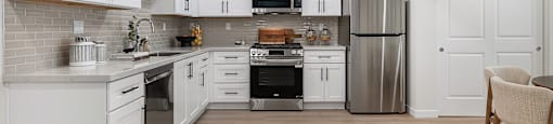 A modern kitchen with white cabinets and stainless steel appliances.
