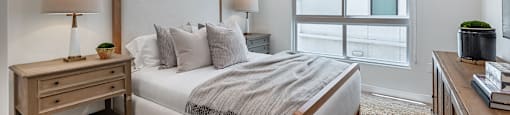 A bedroom with a large bed, a nightstand, and a window.