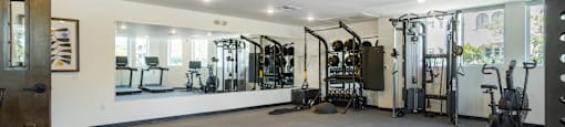 A gym with a variety of equipment including treadmills, weights, and exercise machines.