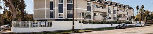 A row of townhouses with a white fence in front.