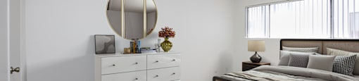a bedroom with a bed and a white dresser and a ceiling fan