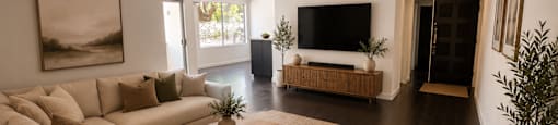 A modern living room with a large couch, a coffee table, and a flat-screen TV.