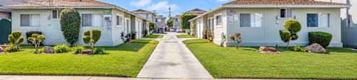 A residential street with houses on both sides and a clear blue sky above.