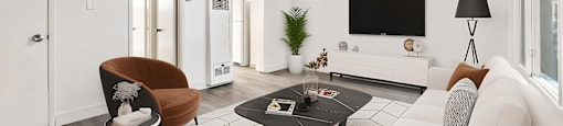 A modern living room with a white couch, a brown chair, and a black coffee table.