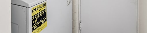 A white dryer and washer are in a small room with a door.