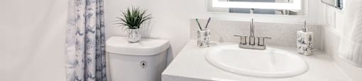 a white bathroom with a mirror and a sink and a toilet
