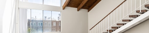 a living room with a staircase and large windows