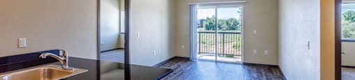 a kitchen and living room with a door to a balcony