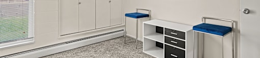 a counselling room with two stools and a cabinet with two drawers