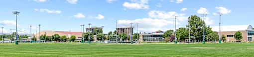 A large grassy field with a clear blue sky and some scattered clouds.