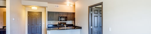 an empty living room with a kitchen and blue doors