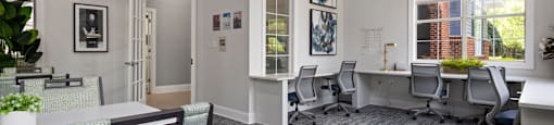 A room with a carpeted floor and white walls has a desk with a chair in front of it.