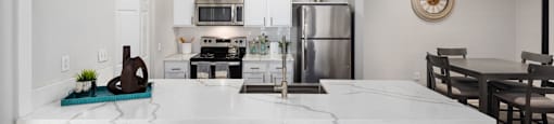 A kitchen with a white counter and blue stools.