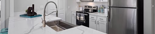A kitchen with a marble counter top and stainless steel appliances.