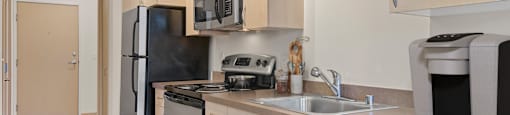 A kitchen with a black fridge, black oven, black microwave, black dishwasher and black coffee maker.