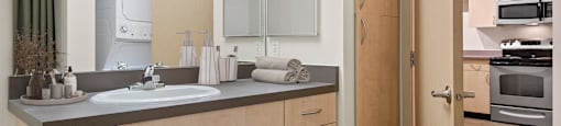 A modern bathroom with a sink, mirror, and wooden cabinets.