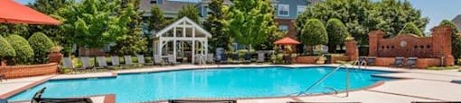 A pool surrounded by lawn chairs and a gazebo.