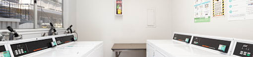 A laundromat with washers and dryers and a table.