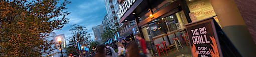 A busy street with people walking and a sign for The Big Grill.  at The 925 Apartments, Washington, DC