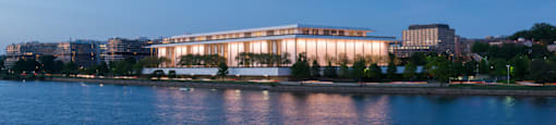 A large building with a glass facade is illuminated from within and is situated on the edge of a body of water.  at The 925 Apartments, Washington, DC