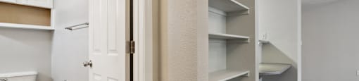 an empty closet in a bathroom with a toilet and shelves