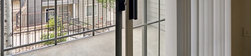 a sliding glass door opens to a balcony with an apartment building