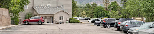 a parking lot with cars in front of a building with mountains in the background