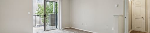 an empty living room with a door to a balcony