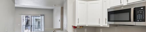 a kitchen with white cabinets and black appliances and a window