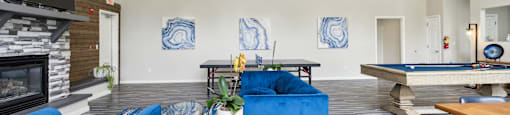 a living room with blue couches and a pool table