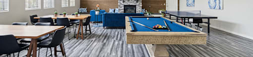 a clubhouse with a pool table and tables and a fireplace