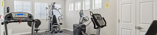 a gym with cardio machines and other exercise equipment at the belgard apartments