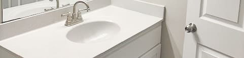 A white bathroom with a sink and mirror.