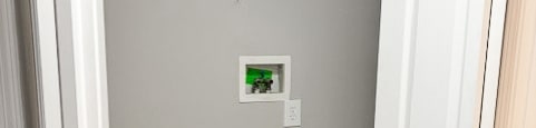 A white door is open to a small closet with a shelf and a light switch.