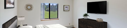 A bedroom with a large bed and a flat screen TV mounted on the wall.