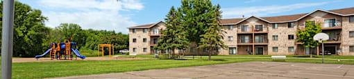 A basketball court with a hoop and apartment buildings in the background.