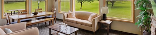 A living room with a large window overlooking a green field.