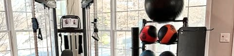A home gym with a variety of equipment including a weight rack, a bench, and a large ball.